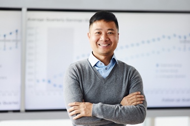 man in sweater standing in front of whiteboard
